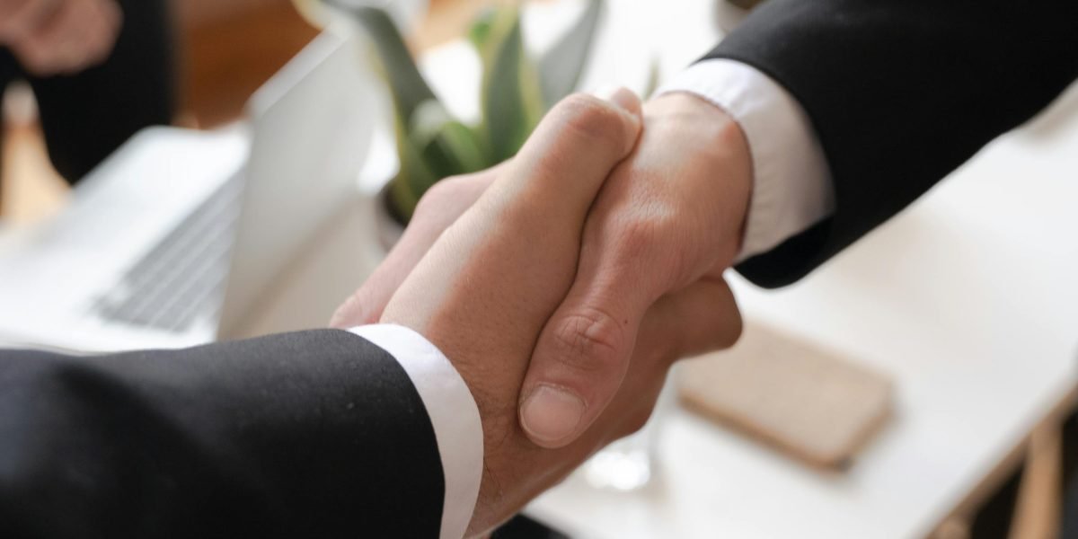 Two business professionals shaking hands after a successful meeting, symbolizing strategic partnerships in the quantum computing sector.