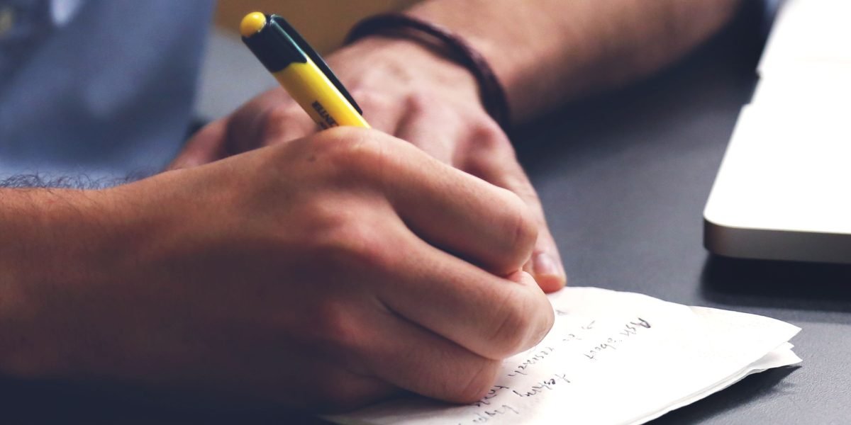 An individual diligently taking notes during a discussion, symbolizing careful evaluation and planning.