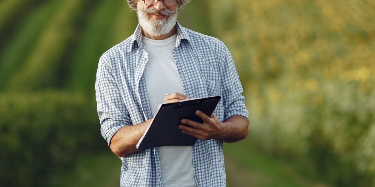 A farmer inspecting healthy crops in a field, symbolizing the benefits of Ag Technologies like yield optimization and input reduction.