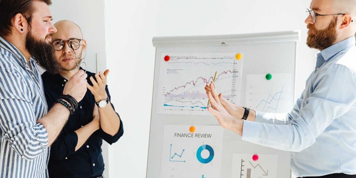 A team of professionals actively discussing and brainstorming ideas around a whiteboard, representing innovation.
